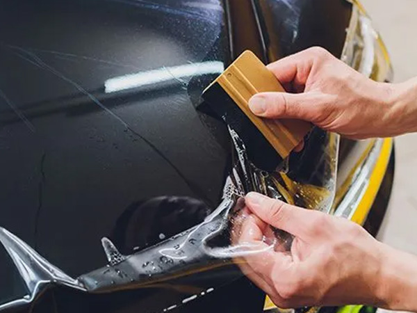 Worker applying 3M paint protection film to car