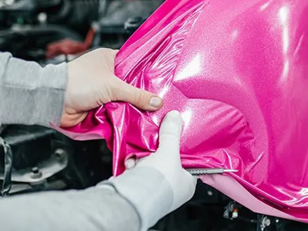 Worker applying pink vinyl car wrap