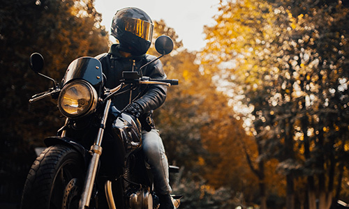 Motorcyclist in a helmet with a classic motorcycle in the fall